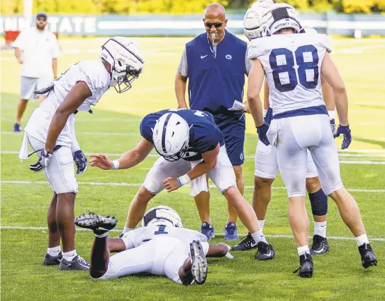  ?? JOE HERMITT/AP ?? Penn State wide receiver KJ Hamler celebrates a reception with quarterbac­k Sean Clifford as coach James Franklin stands near them during practice.