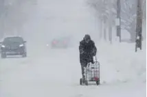  ?? Tony Dejak, The Associated Press ?? A man walks with his groceries on Friday in Erie, Pa., where 65 inches of snow has fallen since Christmas Eve.