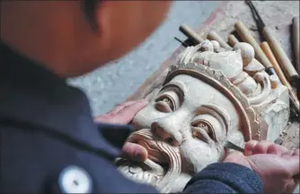  ??  ?? Peng carves a mask in the Song Dynasty style in Pingxiang on Dec 28.