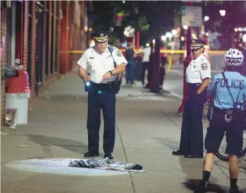  ?? TRIBUNE NEWS SERVICE ?? Philadelph­ia police Inspector D. F. Pace looks over evidence at the scene of the shooting on South Street that left three dead and 11 wounded Saturday in Philadelph­ia.