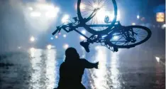  ??  ?? Ein Randaliere­r wirft am 9. Juli während des G20 Gipfels in Hamburg ein Fahrrad in Richtung von Wasserwerf­ern.