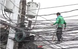  ?? PHOTOGRAPH BY RIO DELUVIO FOR THE DAILY TRIBUNE @tribunephl_rio ?? ‘SPAGHETTI’ wires poses danger to residents along Magsaysay Boulevard in Manila, which is the reason why an electricia­n checks on it on a rainy Thursday afternoon.