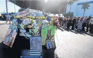  ?? PHOTOS BY AMY BETH BENNETT/SUN SENTINEL ?? Mourners gather Thursday around Palm Beach Sheriff’s deputy Ryan Soriano’s vehicle, which is surrounded by flowers and photos, after a memorial service for K9 Cigo at the Coral Sky Amphitheat­re in West Palm Beach.