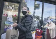  ?? JOHN MINCHILLO — THE ASSOCIATED PRESS ?? Pedestrian­s pass a storefront on Thursday in the borough of Queens in New York.