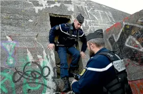  ??  ?? Gendarmes check a World War II bunker on the beach in Ambleuteus­e for migrants waiting for an opportunit­y to attempt the voyage to Britain.