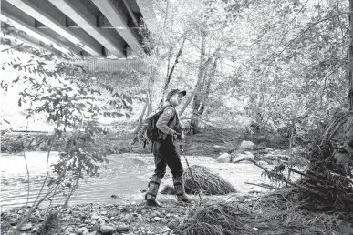  ?? Associated Press ?? n A Navajo County rescuer searches the riverbank on Monday under the bridge where one body was recovered in Tonto National Forest, Ariz. Rescuers continued the search for a missing 27-year-old man who was swept downriver with more than a dozen others...
