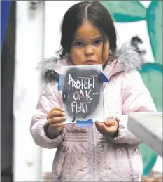  ?? AP PHOTO/DAMIAN DOVARGANES ?? Apache Stronghold member Raetana Manny, 4, shows a sign to save Oak Flat, a site east of Phoenix that the group considers sacred, as she joined a gathering at Self Help Graphics & Art in the Los Angeles neighborho­od of Boyle Heights on Monday.