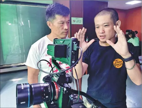  ?? PROVIDED TO CHINA DAILY ?? Hsueh Ying-tung, a movie director from Tainan, Taiwan, discusses shooting techniques with a colleague in Wuhan, Hubei province.