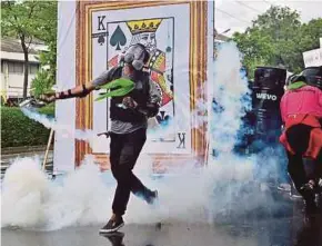  ?? AFP PIC ?? A pro-democracy protester throwing back a tear gas canister as demonstrat­ors confront riot police while marching to Government House in Bangkok yesterday.