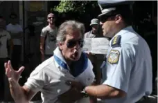  ?? LOUISA GOULIAMAKI/AFP/GETTY IMAGES ?? A Greek police officer prevents a man from approachin­g as he shouts outside the finance ministry in Athens on Tuesday.