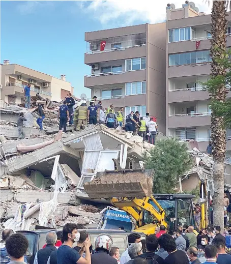  ?? AP ?? Rescue workers and local people try to save residents trapped in the debris of a collapsed building, in Izmir, Turkey, on Sunday.