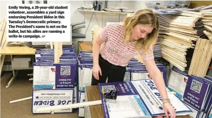  ?? AP ?? Emily Vering, a 20-year-old student volunteer, assembles a yard sign endorsing President Biden in this Tuesday’s Democratic primary. The President’s name is not on the ballot, but his allies are running a write-in campaign.