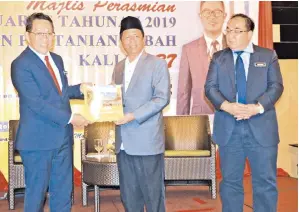  ??  ?? DAUD menerima buku kenangan Taman Pertanian Sabah disampaika­n Idrus.