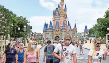  ??  ?? VISITANTES Usan mascarilla como es exigido para asistir al día oficial de reapertura del parque Magic Kingdom en Walt disney World