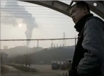  ?? NG HAN GUAN — THE ASSOCIATED PRESS FILE ?? In this file photo, a man looks up near smoke spewing from a chimney near the Jiujiang steel and rolling mills in Qianan in northern China’s Hebei province. Researcher­s say Tuesday that China’s conversion of coal into natural gas could prevent tens of...