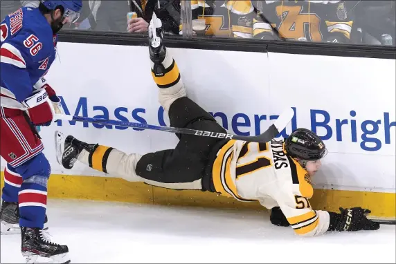  ?? CHARLES KRUPA — THE ASSOCIATED PRESS ?? Boston Bruins center Matthew Poitras is tripped up by New York Rangers defenseman Erik Gustafsson during the second period. Poitras left the ice injured, but returned to finish Saturday’s game.