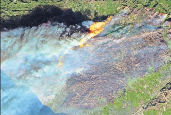  ?? [EUROPEAN SPACE AGENCY/NASA] ?? This Thursday false- color image from a European Space Agency satellite show flames from the Thomas wildfire gashing a portion of Southern California as smoke billows toward the Pacfic Ocean to the west. Untouched areas of vegetation appear in bright...