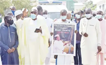  ?? — AFP photo ?? A mourner holds a portrait of the late Guinean singer Mory Kante during his funeral procession in Conakry Guinea.