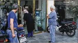  ?? EBRAHIM NOROOZI / ASSOCIATED PRESS ?? People wait in downtown Tehran at a closed money exchange shop. Many of the shops were allowed to reopen Tuesday.