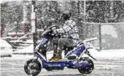  ?? MATT ROURKE / AP ?? A person drives a scooter during a winter snow storm in Philadelph­ia on Tuesday. Some areas of Pennsylvan­ia were hit with as much as 15 inches of snow.