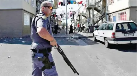  ?? PIETER BAUERMEIST­ER/AFP ?? An armed South African police officer patrols in a street as he responds to a shooting of two alleged gang members in Manenberg, Cape Town, on October 18.