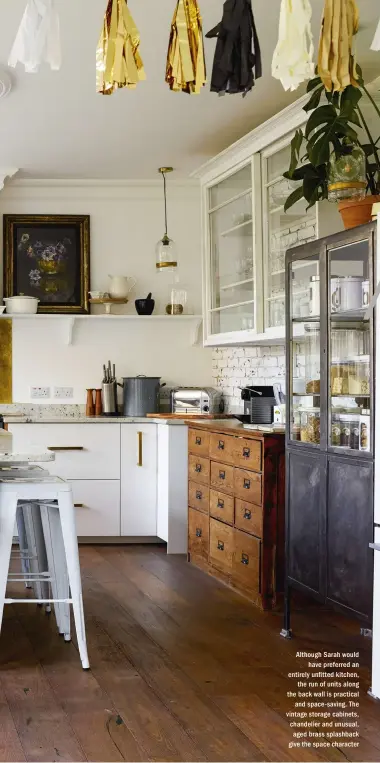  ??  ?? Although Sarah would have preferred an entirely un tted kitchen, the run of units along the back wall is practical and space- saving. The vintage storage cabinets, chandelier and unusual, aged brass splashback give the space character