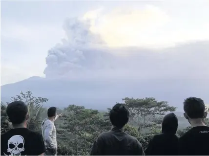  ?? Firdia Lisnawati ?? > Villagers watch the Mount Agung volcano erupting at sunrise in Karangasem, Bali island, Indonesia, yesterday