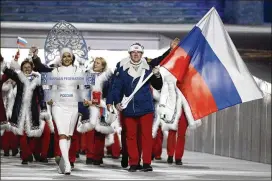  ?? MARK HUMPHREY / ASSOCIATED PRESS ?? Russian bobsledder Alexander Zubkov (carrying the national flag during the 2014 Winter Olympics opening ceremony) was stripped of the two gold medals he won in the two- and four-man events for doping.