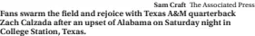  ?? Sam Craft The Associated Press ?? Fans swarm the field and rejoice with Texas A&M quarterbac­k Zach Calzada after an upset of Alabama on Saturday night in College Station, Texas.