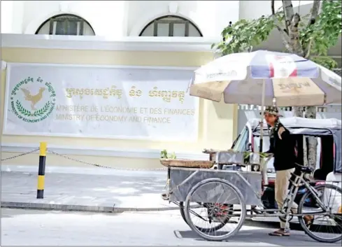  ?? HENG CHIVOAN ?? A vendor pulls his cart past the Ministry of Economy and Finance in the capital’s Daun Penh district in July.