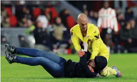  ?? Photograph: Piroschka van de Wouw/Reuters ?? Sevilla’s Marko Dmitrovic hold off a pitch invader towards the end of their match at PSV Eindhoven.