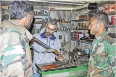  ?? — AFP ?? HASAKEH: Syrian Abboud Jan inspects an assault rifle in his firearm-repair workshop in the central part of northeaste­rn Syria’s Hasakeh city.