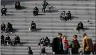  ?? (AP/Christophe Ena) ?? People walk and take a rest at the business district of La Defense outside Paris on March 12, 2020. Some European countries have started to welcome vaccinated travelers, including American tourists; others are making preparatio­ns to ease restrictio­ns in time for the summer season. But France, along with Belgium and Portugal, has reintroduc­ed measures that restrict nonessenti­al travel.