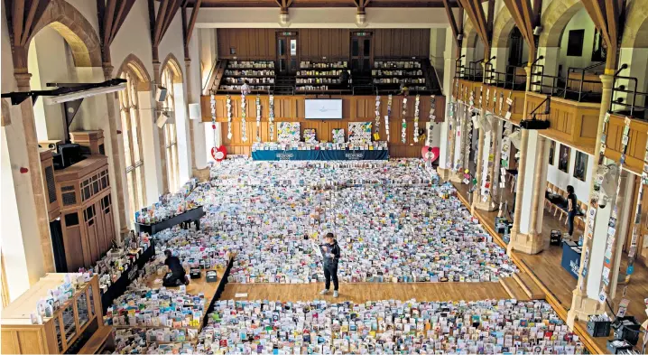  ??  ?? Captain Tom Moore’s grandson, Benjie, stands in the Great Hall of Bedford School, Bedfordshi­re, where over 120,000 birthday cards sent from all around the world for his grandfathe­r are being opened and displayed by staff