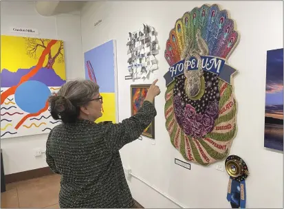  ?? MARY BENJAMIN- FORT BRAGG ADVOCATE-NEWS ?? Chris Hagie, one of the founders of Edgewater Gallery, points out the materials used in “Hope Dies Last,” the First Place winner in the gallery's national juried show.