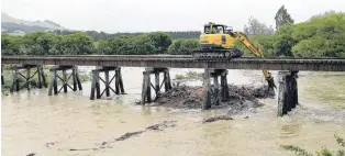  ?? PHOTO: STEPHEN JAQUIERY ?? Over the line . . . A digger clears debris from a rail bridge on the Shag River north of Palmerston.