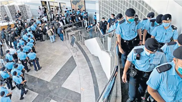  ??  ?? Hundreds of police officers search the headquarte­rs of Next Digital following the arrest of the media company’s owner, Jimmy Lai, below, centre, at his home in Hong Kong. Thousands watched a live broadcast of the office raid