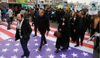  ?? ATTA KENARE/AFP/GETTY IMAGES ?? Iranians walk on a U.S. flag during Friday’s rally. Iran’s president called the new Trump administra­tion “a problem.”