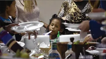  ??  ?? Liana Hill, of First Baptist Church on New Street, looks at her choices for food while other parishione­rs fix their plates at First Baptist Church’s Thanksgivi­ng potluck on Nov. 19.