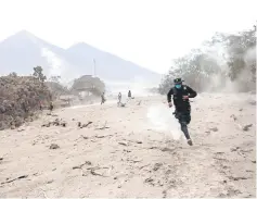  ?? — Reuters photo ?? A police officer runs away after Fuego volcano spew new pyroclasti­c flow.