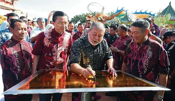  ??  ?? Sultan Ibrahim (middle) signing a plaque during the launching of the Green Garden where the biggest dragon tunnel in the world is situated at the Che Ann Khor Associatio­n in Yong Peng in November last year. Looking on is Tee (second from left).