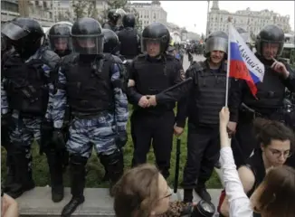  ?? PAVEL GOLOVKIN, THE ASSOCIATED PRESS ?? Police watch the scene during a demonstrat­ion in downtown Moscow on Monday. Opposition leader Alexei Navalny hoped to repeat the nationwide protests that rattled the Kremlin three months ago.