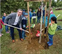  ?? ?? Erst einmal einen Nussbaum pflanzen: Bildungsmi­nister Claude Meisch bei der offizielle­n Einweihung des Schulgarte­ns mit Reckinger Grundschül­ern.