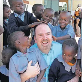  ?? [AP PHOTO] ?? Greg Eubanks, CEO of an adoption agency in Washington state called WACAP, is surrounded by students from a community elementary school in 2011 in Nairobi, Kenya. Eubanks says his agency and other U.S. adoption agencies dealing in internatio­nal adoption...