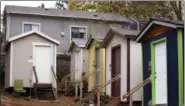  ?? ELAINE THOMPSON — THE ASSOCIATED PRESS ?? A row of tiny houses at a homeless encampment stand in view of a full-size home behind, in Seattle. Tiny homes could be the solution to all kinds of housing needs, offering warmth and security for the homeless, an affordable option for expensive big...