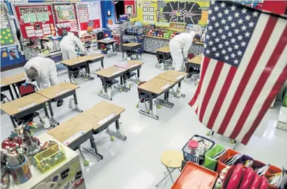  ?? Colter Peterson, St. Louis Post- Dispatch ?? Workers clean a classroom at Richard A. Simpson Elementary School in Arnold, Mo. The school went to fully virtual learning on Nov. 2.