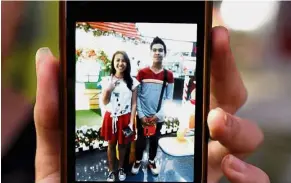  ??  ?? In loving memory: (Above) Shirley, Kian’s sister, showing a picture of herself with her brother on a cellphone and (right) people watching the funeral procession for the teenager going by in Caloocan. — Reuters