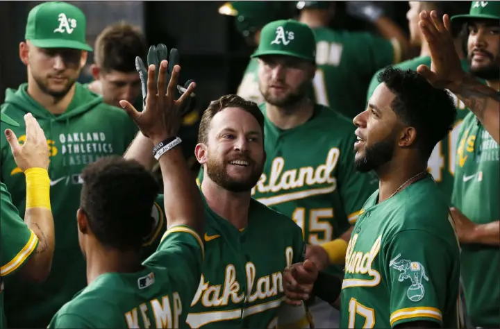  ?? Ray Carlin The Associated Press ?? Jed Lowrie of the Oakland Athletics is greeted in the dugout after hitting a home run against the Texas Rangers. The A’s are 52-40 coming out of the All-star break.