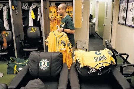  ?? Michael Macor / The Chronicle ?? At the Coliseum, A’s assistant clubhouse manager Brian Davis packs up uniforms Monday after the conclusion of the season.