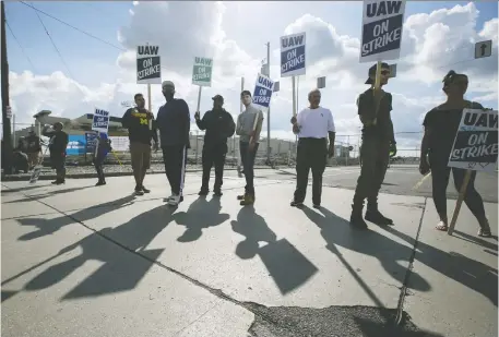  ?? ANTHONY LANZILOTE/ BLOOMBERG FILES ?? Demonstrat­ors hold signs during a United Auto Workers strike outside the GM assembly plant in Flint, Mich., in September. Automakers are scaling back operations as they grapple with the global shift to new technology and the fallout from trade wars.